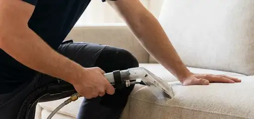 Professional upholstery cleaner deep-cleaning a fabric sofa with a handheld extraction tool, Dayton, OH.